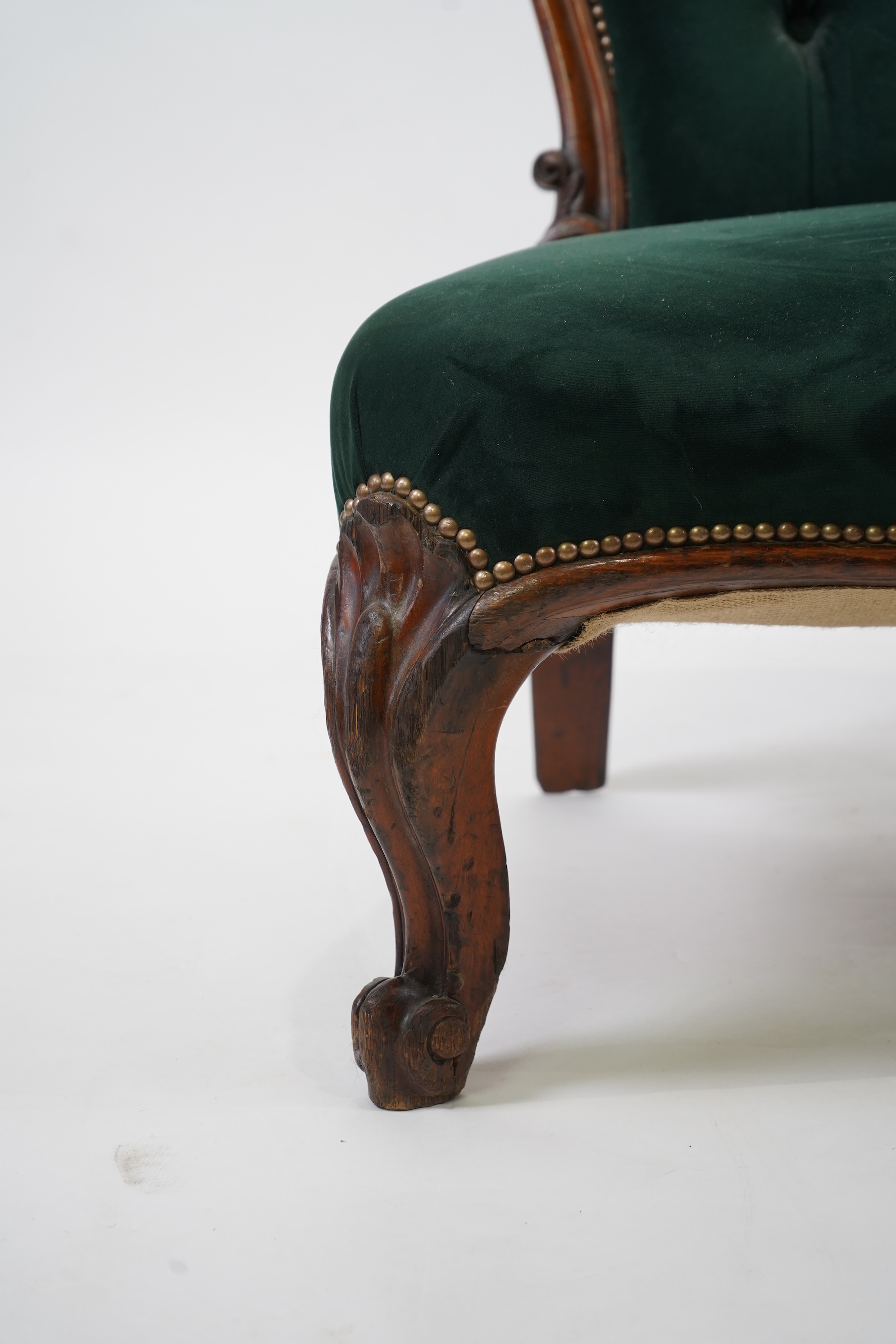 A pair of Victorian carved oak settees, recently re-upholstered in deep buttoned green velvet, the scroll carved crest rails over serpentine seats on cabriole front legs, 160cm wide, 96cm high, Provenance - previously gi